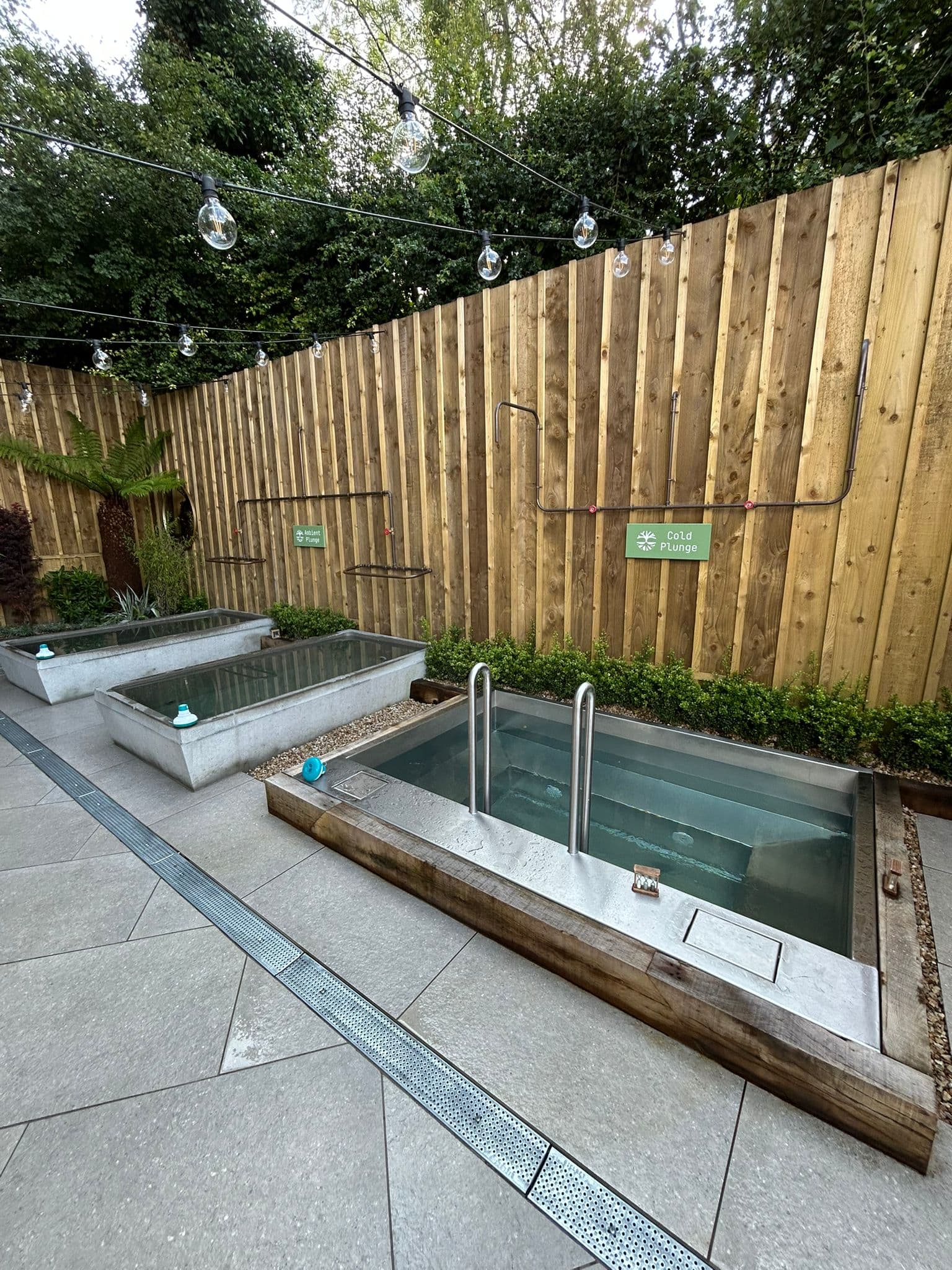 Three ice-cold plunge pools under festoon lights on the tiled outdoor spa floor.